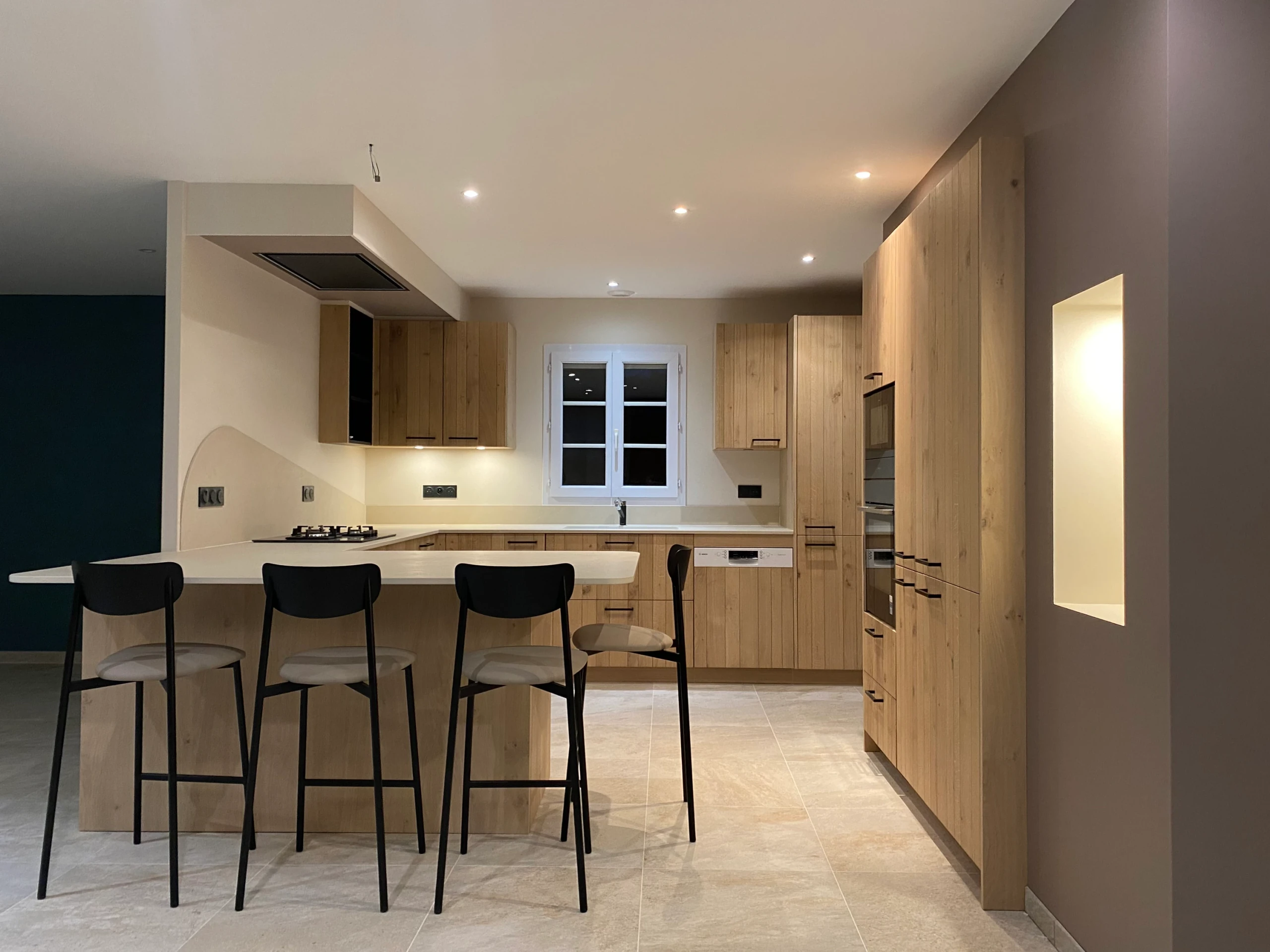 Vue d’ensemble : façades à décor bois clair, plans crème et niche éclairée.