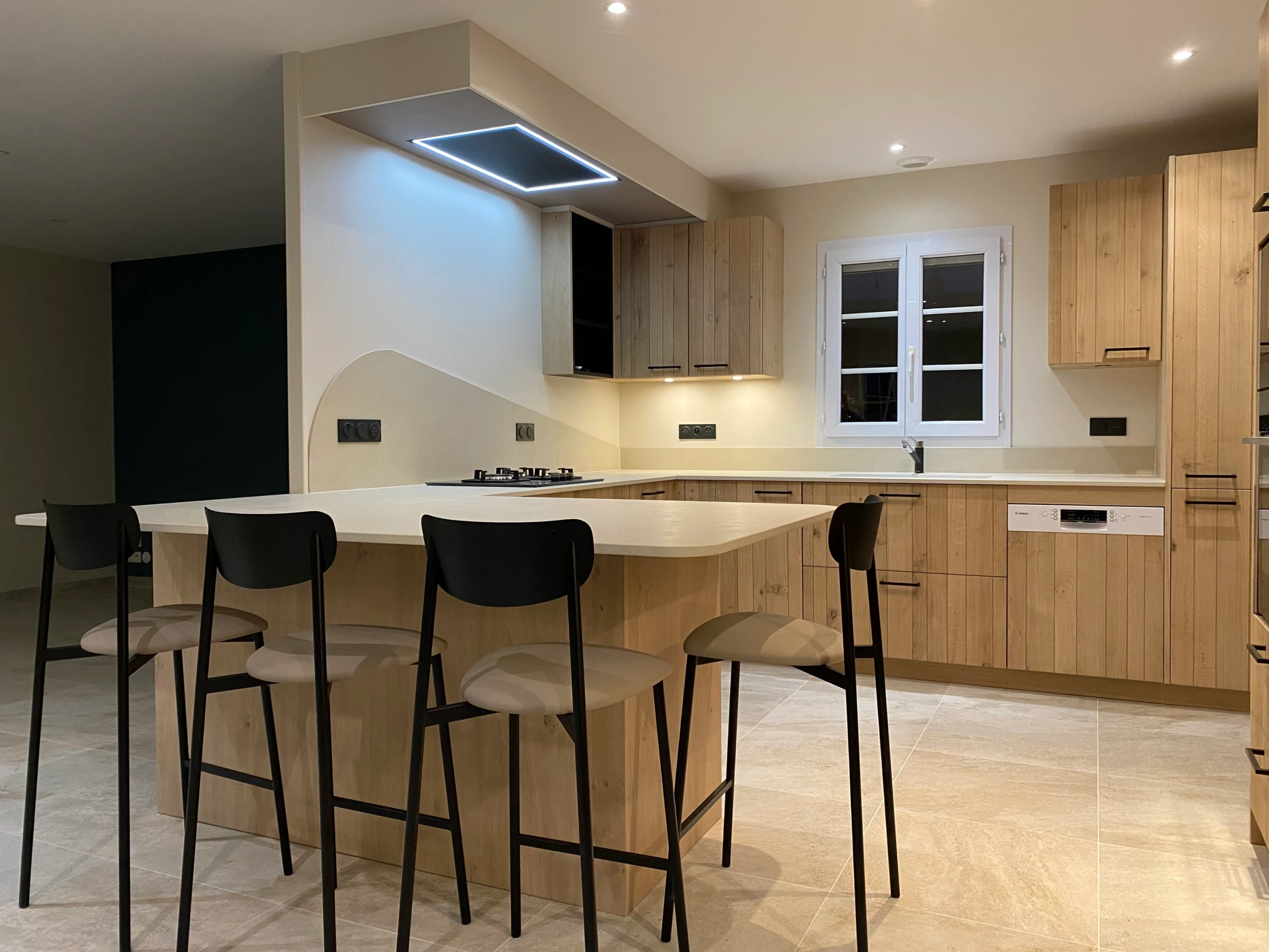 Le retour repas aux angles arrondis et les assises noires prolongent la cuisine.
